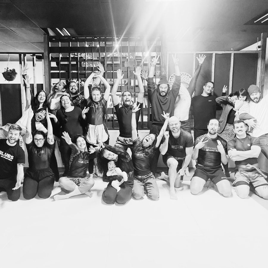 Groupe d'élèves du cours d'introduction au BJJ, bras levés et souriants, après leur dernier cours