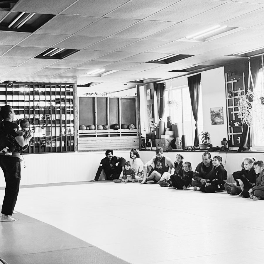 Une instructrice s'adresse à un groupe de parents et d'enfants assis sur le tatami pendant un cours Parents-enfants